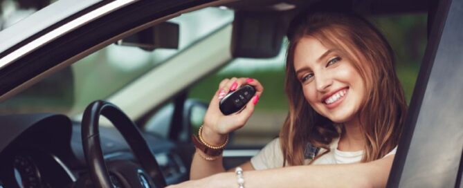 woman smiling in car with keys in her hand