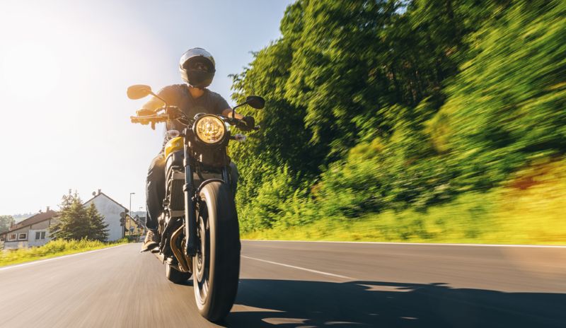 man riding a motorcycle on an empty and rural road