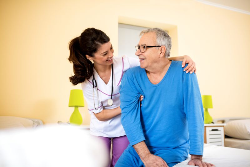 Young female nurse accompanying an older male patient