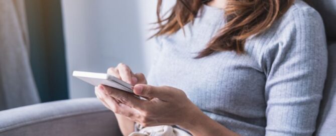 Woman sitting on her couch scrolling through her phone
