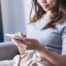 Woman sitting on her couch scrolling through her phone